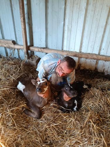 a man bending down next to two baby goats at ferme pedagogique des pennetieres in Montcorbon