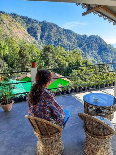 a woman sitting in a chair looking at the mountains at Queen's Nest Homestay in Takdāh