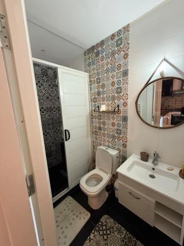 a bathroom with a toilet and a sink and a mirror at Appartement lumineux en bord de mer in Sousse