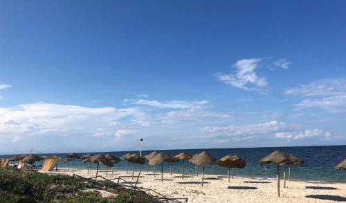 a group of umbrellas on a beach with the ocean at Appartement lumineux en bord de mer in Sousse