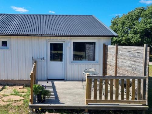 a white shed with a wooden deck and a fence at Stugor - Lgh sodra Oland in Mörbylånga
