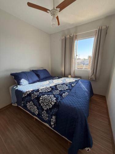 a bedroom with a bed with a blue comforter and a window at Canoas Ulbra Parkshopping in Canoas