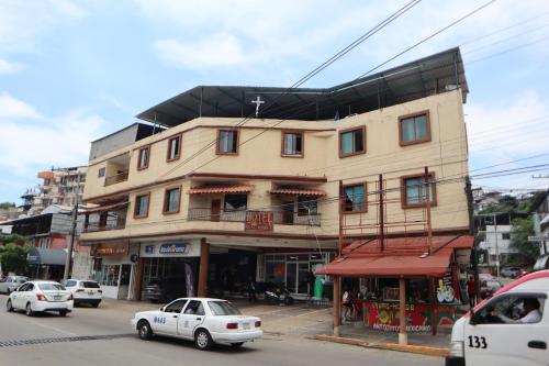 a building on the corner of a street with cars at Hotel Real Monrey in Zihuatanejo