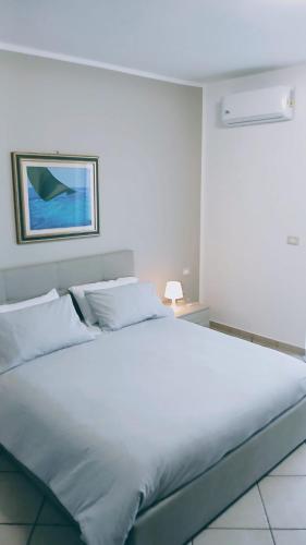 1 cama blanca en un dormitorio con una foto en la pared en la casa di Camilla, en Volvera