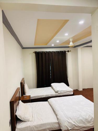two beds in a room with a black curtain at Aba-SHAH GUEST HOUSE SKARDU in Skardu