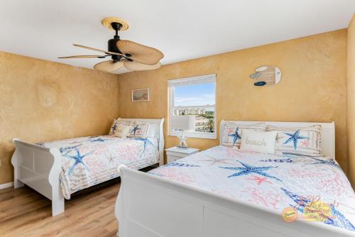a bedroom with two beds and a ceiling fan at Sea Oats 501 in St Pete Beach
