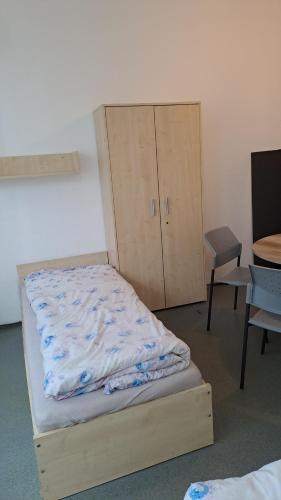 a bed in a room with a cabinet and a chair at Hotel Hranice 