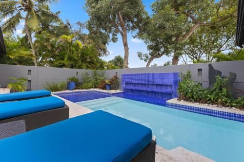 a swimming pool with blue chairs and a fence at Villa with golf course views in San Rafael del Yuma