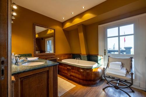 a bathroom with a tub and a sink and a chair at Chateau de la Triboulette in Vouzeron