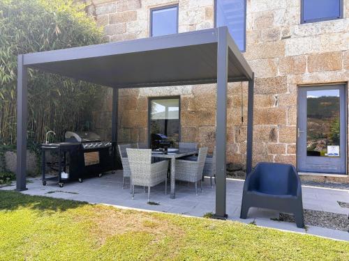 a pavilion with chairs and a table in a yard at A casa dos Parladoiros in Mos