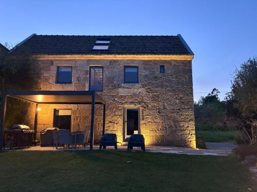 a stone house with a table and chairs in front of it at A casa dos Parladoiros in Mos