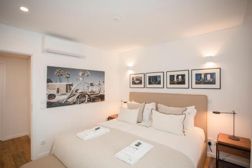 a white bedroom with two beds and pictures on the wall at Liiiving in Gaia - Cooper Residence Apartment II in Vila Nova de Gaia