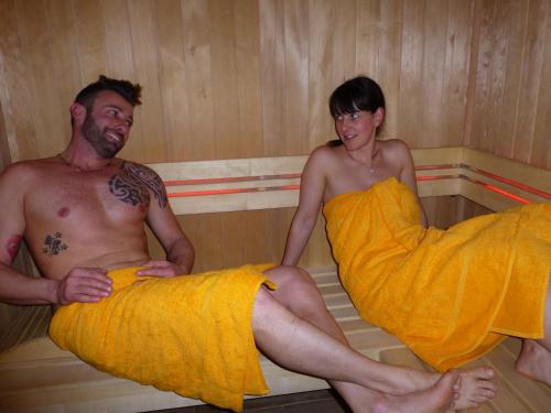 a man and a woman sitting in a sauna at Villa Adria B&B in Canazei