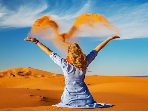a woman in the desert with her arms outstretched at Desert Medina Camp in Merzouga