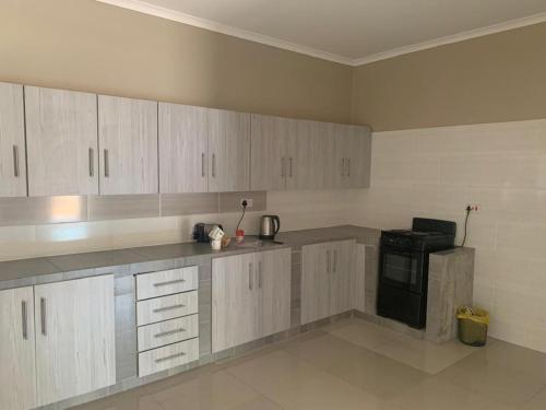 a kitchen with white cabinets and a black appliance at MB guesthouse in Kasane