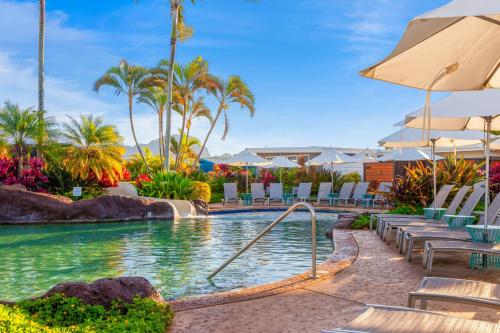 a pool at a resort with chairs and umbrellas at Prince Kuhio 110 in Koloa
