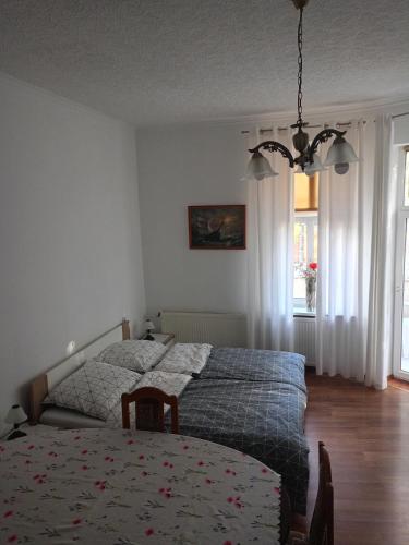 a bedroom with two beds and a table and a chandelier at Kamienica z Balkonem - pokoje gościnne in Reszel