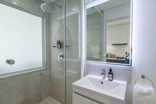 a white bathroom with a sink and a shower at Stylish Urban Retreat in Hout Bay