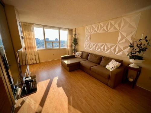 a living room with a couch and a large window at Lower Penthouse Suite with Pools & Sunset Views in Toronto