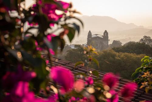 a view of a building with pink flowers in the foreground at Posada del Tepozteco - Hotel & Gallery in Tepoztlán