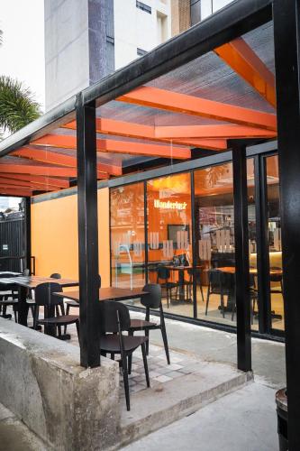 a restaurant with tables and chairs and glass windows at Wanderlust Hostel in Maceió
