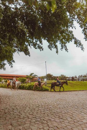 a group of people riding horses down a road at Hotel Fazenda Monte Castelo in Gravatá