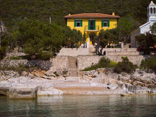 a yellow house on the shore of a body of water at Kapetanova kuća in Martinšćica
