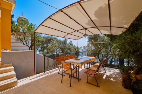 a patio with a table and chairs on a balcony at Kapetanova kuća in Martinšćica