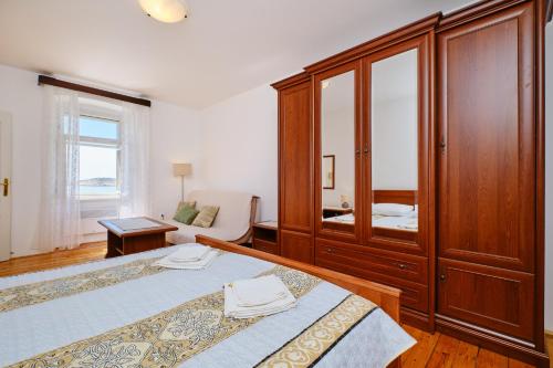 a bedroom with two beds and a large wooden cabinet at Kapetanova kuća in Martinšćica