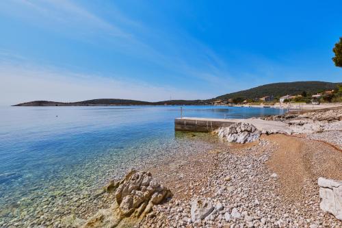 a beach with a pier in the water at Kapetanova kuća in Martinšćica