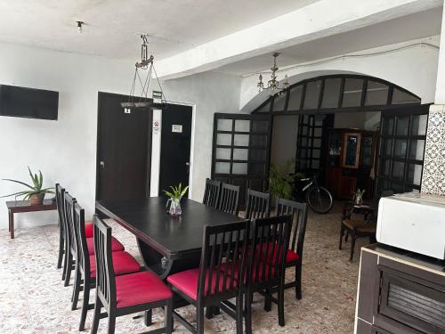 a dining room with a black table and red chairs at Hotel y Hostal Casa Don Alfonso in Valladolid