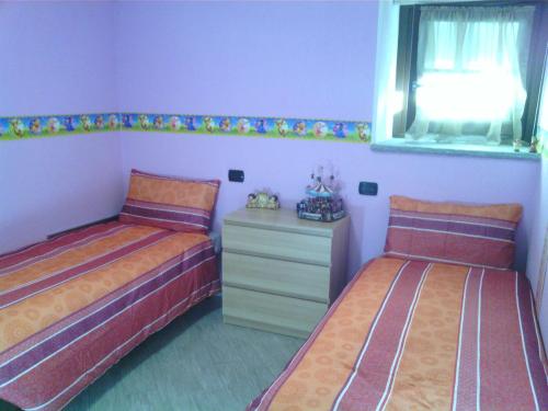 - une chambre avec 2 lits, une commode et une fenêtre dans l'établissement Casa Valtournenche, à Valtournenche