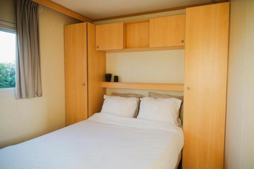 a small bedroom with a bed and wooden cabinets at chalet fazant in Serooskerke