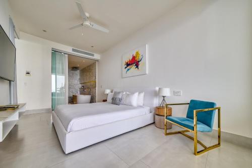 a bedroom with a white bed and a blue chair at Maxwell Residences at Indah in Puerto Vallarta