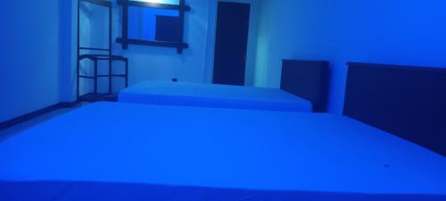 two beds in a room with a blue light at Secret Relax Inn Hotel & Guest House in Kataragama