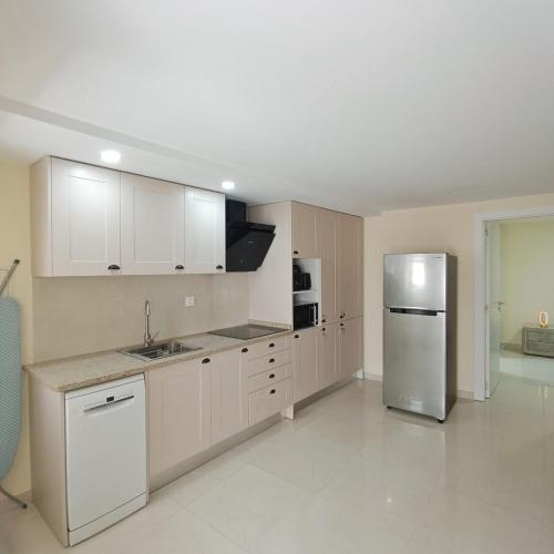 a kitchen with white cabinets and a stainless steel refrigerator at Casa Estrela Em Flor in Covilhã
