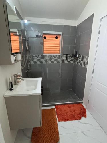 a bathroom with a sink and a shower with an orange window at Cozy and Simple Escape in Kupuis
