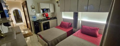 ein kleines Zimmer mit 2 Betten und einer Küche in der Unterkunft Studio Carmen with a Pool View in El-Alamein