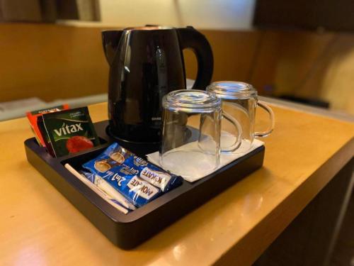 a tray with a coffee pot and two cups and snacks at Hotel Restauracja Tenis Kortowo in Poznań
