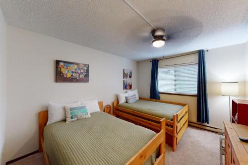 Un dormitorio pequeño con dos camas y una ventana. en Between the Pines, en Steamboat Springs