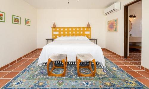a bedroom with a bed with two chairs on a rug at Casa Bella Vista in Nopoló