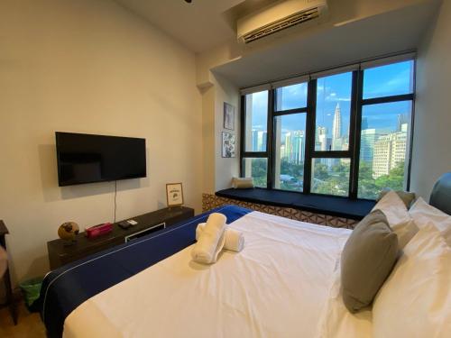 a bedroom with a bed with a tv and a large window at Ceylonz Suites by Stayla in Kuala Lumpur