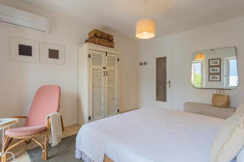 a white bedroom with a white bed and a pink chair at Il Porticciolo by Rent All Como in Carate Urio