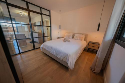 Un dormitorio con una cama blanca y una ventana grande. en T2 cosy proche nature et centre- La Verrière, en La Possession