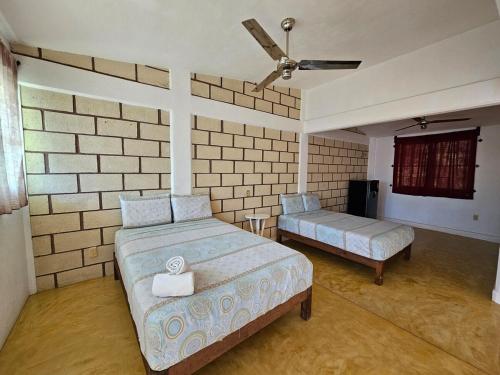 une chambre avec deux lits et un ventilateur de plafond dans l'établissement Casa Amarilla, à Barrio Nuevo