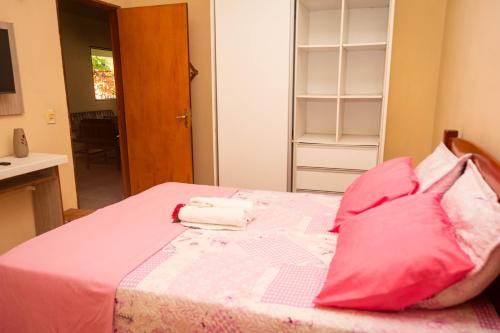 a bedroom with a bed with pink sheets and pillows at Casa de Hospedagem Cajueiro in Jijoca de Jericoacoara