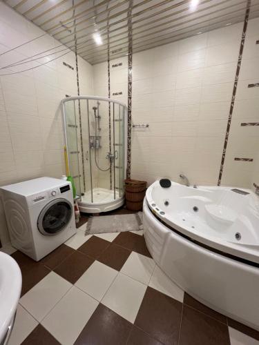 a bathroom with a tub and a washing machine at Апартаменти на Сихові in Lviv