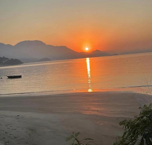 a sunset on a beach with a boat in the water at Bela vista in Mangaratiba