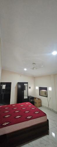 a bedroom with a large bed with a red blanket at Vashistfarmsadhranabamirpur in Gurgaon