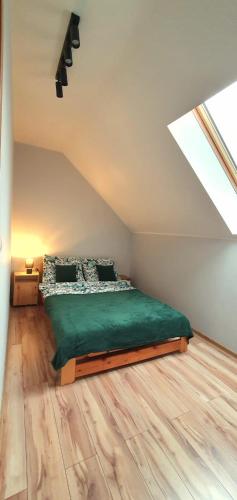 a bedroom with a green bed in a attic at Biały Źagiel in Jantar